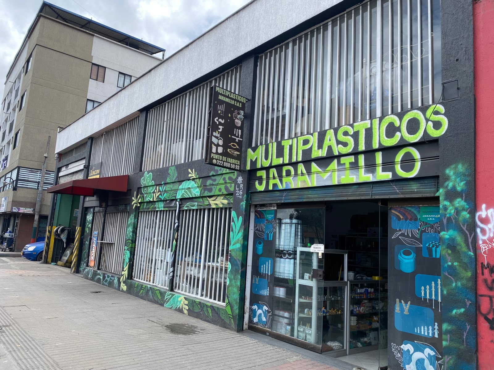 Fachada del punto de fábrica de Multiplásticos Jaramillo en la Avenida Caracas, con el mural verde y el aviso de la empresa