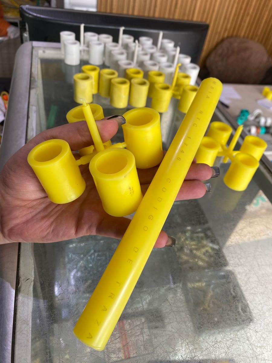 Una mano sostiene uniones de polietileno amarillas por termofusión socket y un tramo de tubo de gas, sobre el mostrador con el resto de las piezas